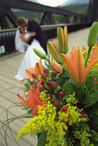 Bouquet de fleurs avec mariée et marié baisers en arrière-plan — Photo