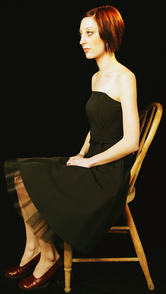 Beautiful female model in black dress sitting on chair