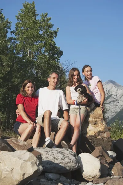 全家人坐在岩石于山里，有他们的狗 — 图库照片