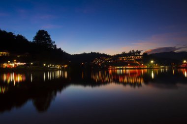 Mae Hong Son / Tayland - 31 Ekim 2021: Baan Rak Thai Village Light Günbatımı Alacakaranlık Nehri 'ne yansıyan lambalar.
