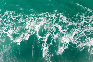 Dalgalar okyanus suyu arka planında kabarcıklar oluşturur.