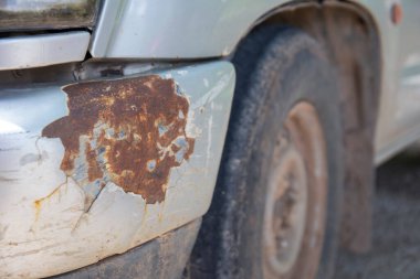 The old car bumper had a crash causing the paint to crack and rust.
