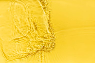 Waves on clear water surface, yellow abstract background.