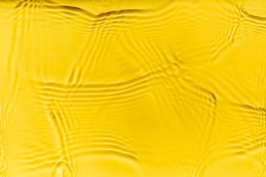Waves on clear water surface, yellow abstract background.