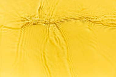 Waves on clear water surface, yellow abstract background.