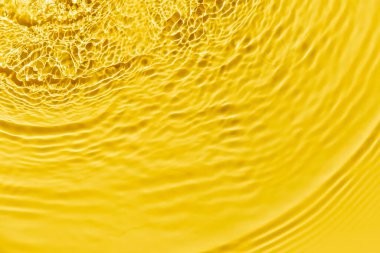 Waves on clear water surface, yellow abstract background.