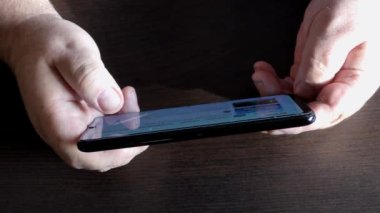Adam akıllı telefondan haberleri izliyor. 