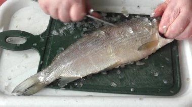 Şef çiğ balığı bıçakla soyar. 