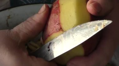 Şef patatesleri bıçakla soyar. 