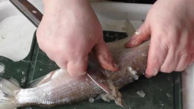 Şef çiğ balığı bıçakla soyar. 