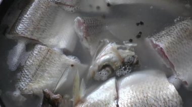 Aşçı tencerede balık pişirir. 