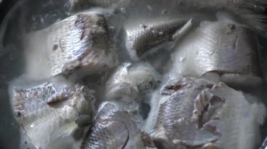 Aşçı tencerede balık pişirir. 