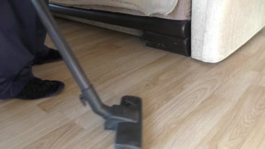 Bir adam evi elektrikli süpürgeyle temizliyor. 