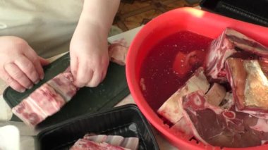 chef cuts venison with a knife, raw deer meat