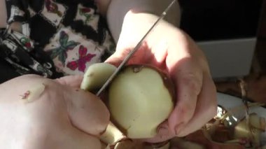 Şef çiğ patatesleri bıçakla temizler. 