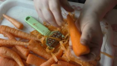 Şef taze havuçları bıçakla temizler. 