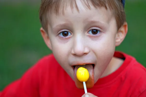 Eating a yellow lollipop — Stock Photo, Image