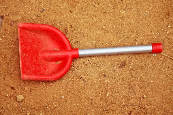 Rode speelgoed spade in de zandbak — Stockfoto