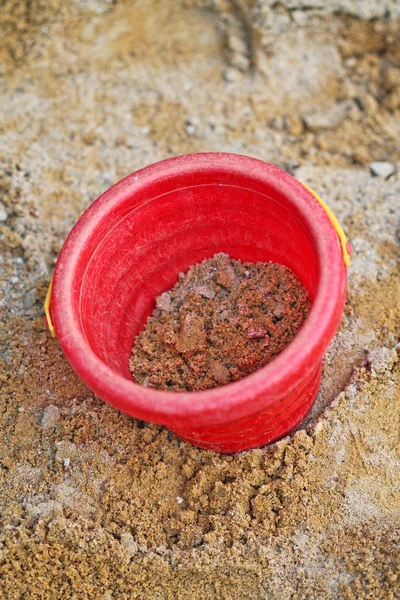 Roter Eimer im Sandkasten lizenzfreie Stockfotos