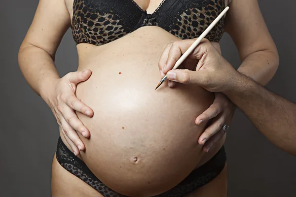 Escribir en el vientre de una mujer embarazada — Foto de Stock