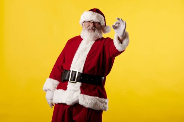 Noel Baba sarı arka planda iyi bir jest yapıyor