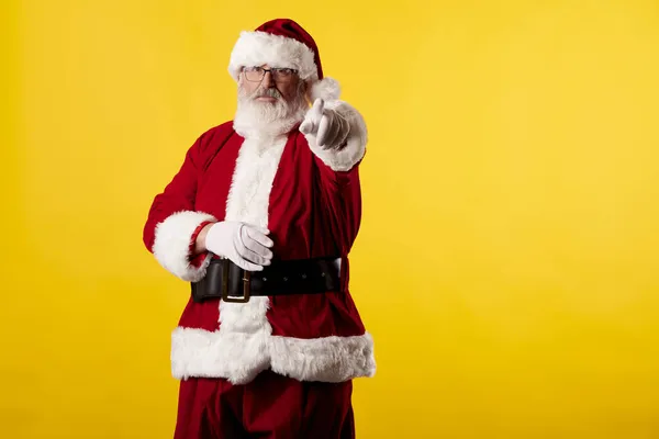 Noel Baba Sarı Arka Plandaki Kamerayı Işaret Ediyor — Stok fotoğraf