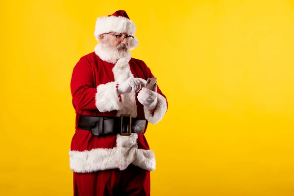 Kerstman Met Behulp Van Een Mobiele Telefoon Gele Achtergrond — Stockfoto