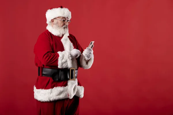 Kerstman Met Behulp Van Een Mobiele Telefoon Rode Achtergrond — Stockfoto