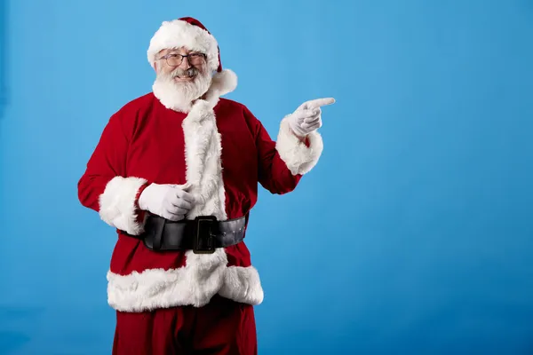 Noel Baba parmağını mavi arka plandaki reklam panosuna gösteriyor.