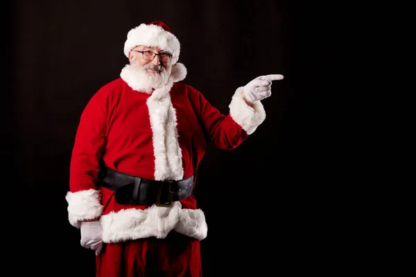 Noel Baba siyah arka plandaki reklam panosunu işaret ediyor.