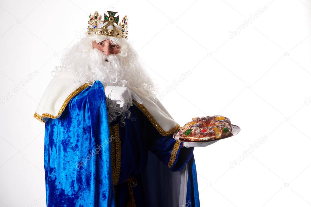 smiling king magician holding a roscon de reyes in his hand on a white background