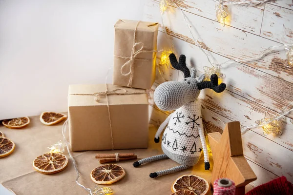 Decoração para o Natal em estilo ecológico com suas próprias mãos. Cervos de brinquedo de malha, alces, presentes em papel artesanal, laranjas secas, estrela de madeira. Imagem De Stock