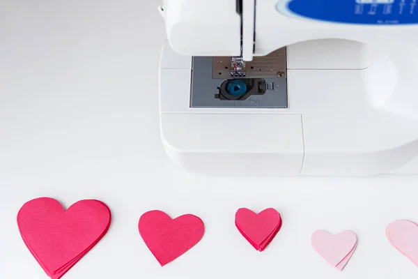 Máquina de costura e corações de papel. O processo de fazer uma grinalda. Conceito para costurar com amor, Dia dos Namorados. — Fotografia de Stock