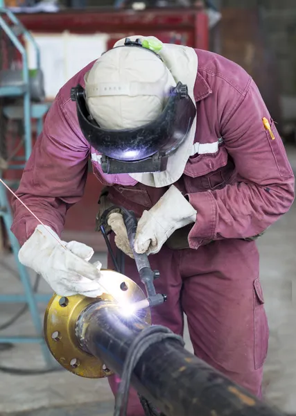 Artesanato em um terno de segurança está soldando um tubo de metal — Fotografia de Stock