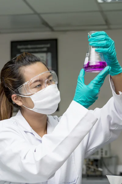 Lady holding och tittar på kemikalie i test glas — Stockfoto