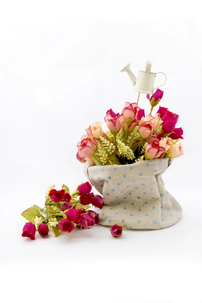 Roses and small watering pot in fabric vase on white — Stock Photo, Image