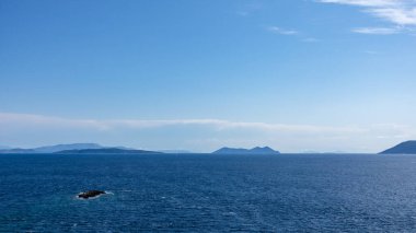 Lefkada Yunanistan adasındaki mavi İyon deniz manzarası. Uzak adaların üzerinde alçak bulutlarla aydınlık bir gün. Açık deniz arkaplanı