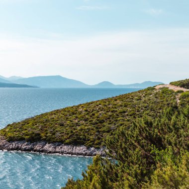 Yunanistan 'da açık mavi bir günde yeşillik, yüksek uçurumlar, güneşli deniz kıyıları. Manzaralı seyahat yeri. Lefkada adası, İyon deniz kıyısı. Renk sınıflandırılmış