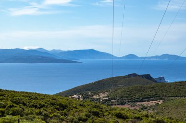 Yunanistan 'daki Lefkada adasının yeşil manzarası. Yeşil ormanlık, mavi gökyüzü ve elektrik destek hattı var. Akdeniz enerji altyapısı