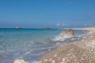 Sahilde beyaz çakıl taşları, Yunanistan 'ın Lefkada adasının kıyılarında açık gök mavisi renginde su fışkırtıyor. İyon Denizi 'ne yaz tatili