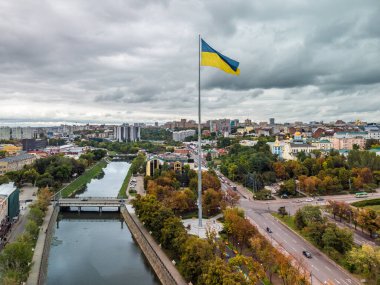 Ukrayna bayrağıyla bayrak direği, destansı gri sonbahar bulutları, Ukrayna 'nın Kharkiv kentindeki Svyato-Pokrovsky Manastırı yakınlarındaki Lopan ırmağının üzerinde şehir havası.