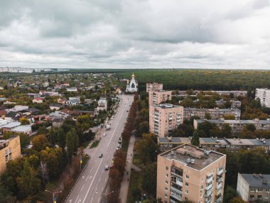 Dramatik bulutlu şehir manzarası. Kharkiv şehri Pavlovo Pole bölgesi, Nauky Caddesi, kilise, çok katlı evler ve sonbahar ormanı manzaralı.