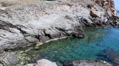 Yunanistan 'ın açık mavi gök mavisi sularıyla yüksek kayalık sahil kayalıkları. Ege Denizi vahşi doğası. Yaz güneşli deniz manzarası