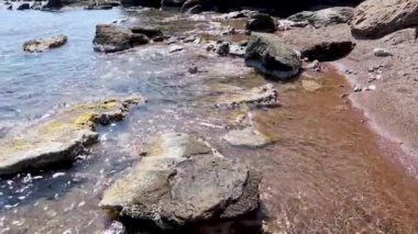 Vahşi kayalık plaj manzarası. Yunanistan 'daki temiz Ege deniz suyunda güneş ışığı ve deniz yosunu olan su altı kayaları. Vahşi deniz doğası