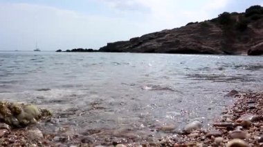 Deniz kıyısı yumuşak dalgaları, çakıl taşı plajı temiz su manzarası, Yunanistan, Atina ve Ege denizlerinde güneş parlıyor. Deniz sahilinde yaz tatili