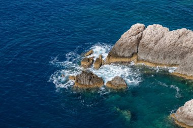Mavi İyon denizindeki kayalara vuran berrak beyaz dalgalar. Yunanistan 'ın Lefkada adasında yaz doğası. Üst hava görüntüsü