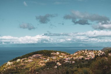 Yunanistan 'ın Lefkada adasında mavi deniz kıyısına yakın yeşil tepelerde turuncu kiremitli çatıları olan geleneksel Yunan köyü. Yazın Avrupa 'yı dolaş. Renk sınıflandırılmış
