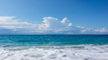 Yunanistan 'ın Lefkada adasının sahillerinde mavi fırtına dalgaları ve destansı bulutlu beyaz köpük. İyon Denizi 'ne yaz tatili