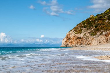 Yunanistan 'ın Lefkada adasının sahillerinde, gök mavisi dalgaları ve canlı günbatımı ışığında beyaz köpüklü Mylos kumlu plajı. İyon Denizi 'ne yaz tatili