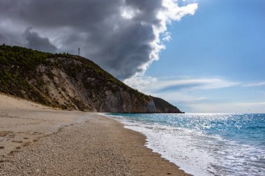 Güneşli sahillerde, Mylos sahilinin üzerinde yüksek uçurumları ve mavi deniz manzarası olan fırtınalı bulutlar. Yunanistan 'daki Lefkada adası. İyon Denizi 'ne yaz yolculuğu